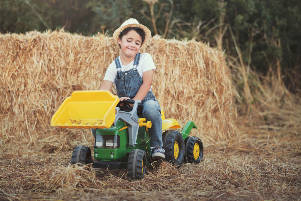 Enfant jouant dans un champ avec un tracteur pour s'amuser